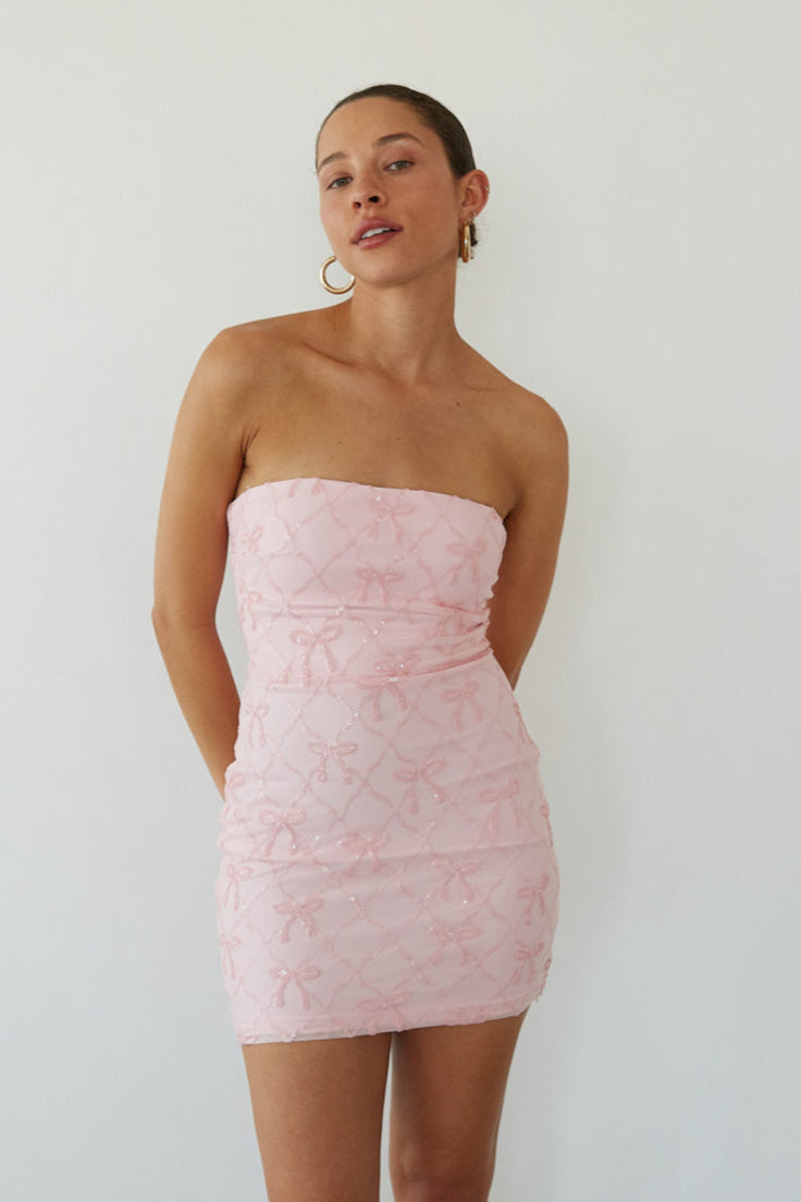 pink-image | Woman wearing a light pink strapless dress against a plain background