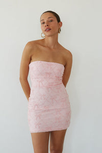 pink-image | Woman wearing a light pink strapless dress against a plain background