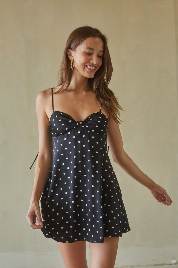 black-image | Woman wearing a black polka dot dress against a beige background