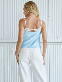 Woman wearing a light blue top and white pants against a white background