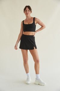 Fitted black activewear skort with side slit and built-in shorts with pockets