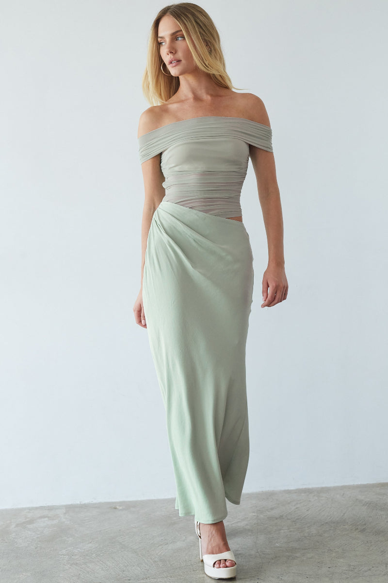 Woman wearing a light green off-shoulder top and skirt set against a plain background