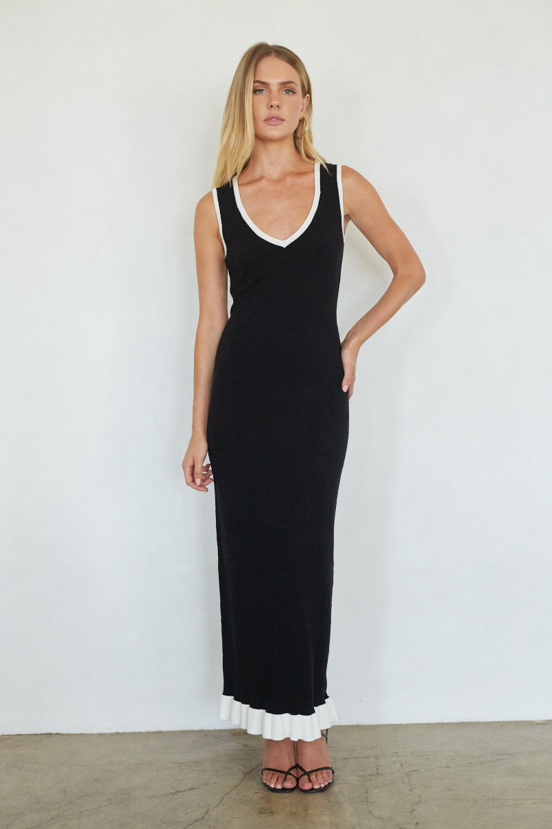 Woman wearing a black dress with white trim against a white background