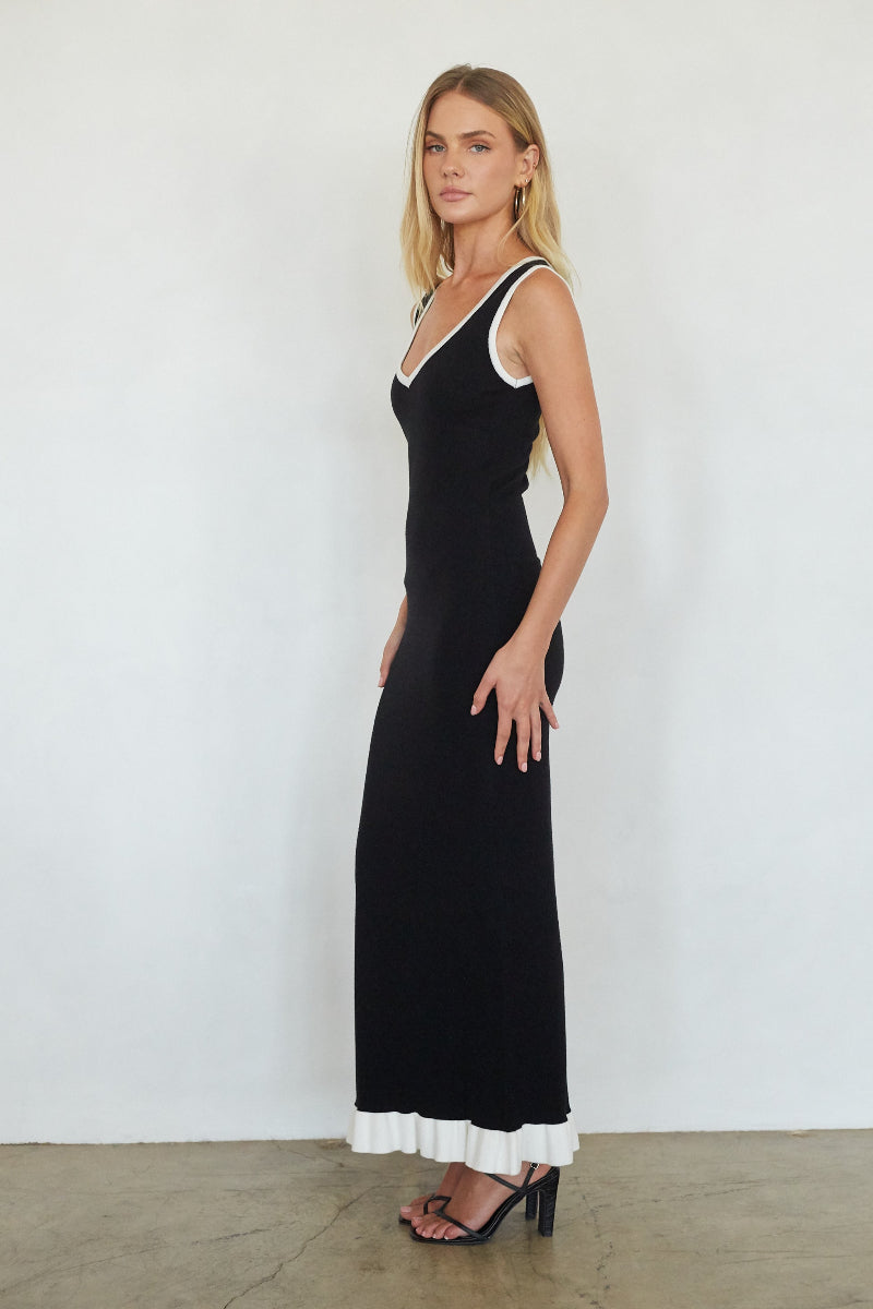 Woman wearing a black dress with white trim against a white background