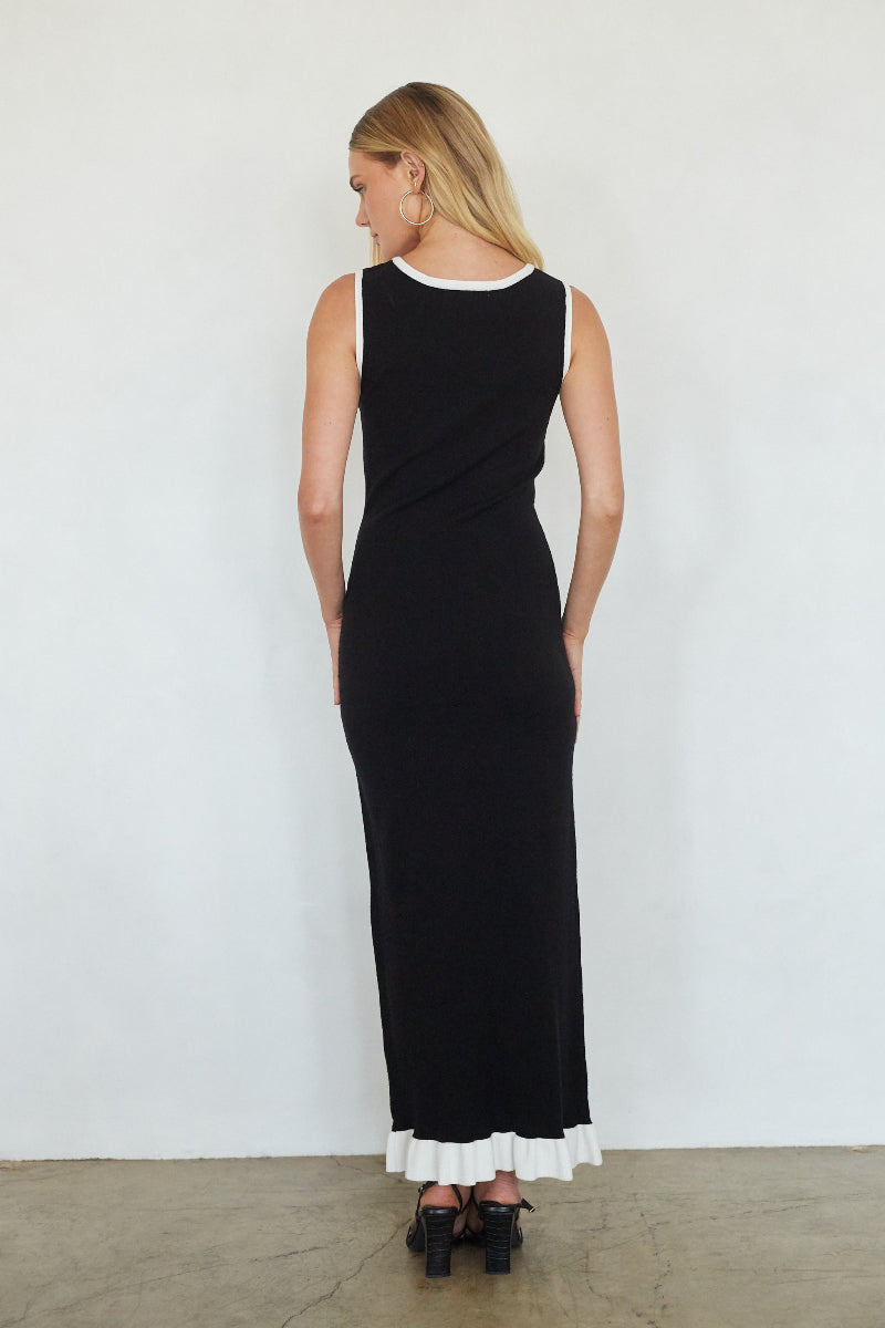 Woman wearing a black dress with white ruffled hem against a white background