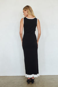 Woman wearing a black dress with white ruffled hem against a white background