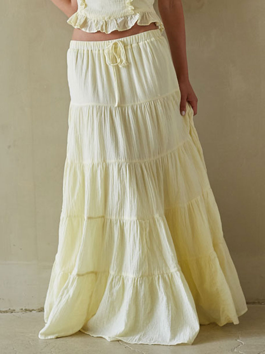 Woman wearing a long, tiered cream skirt against a plain background
