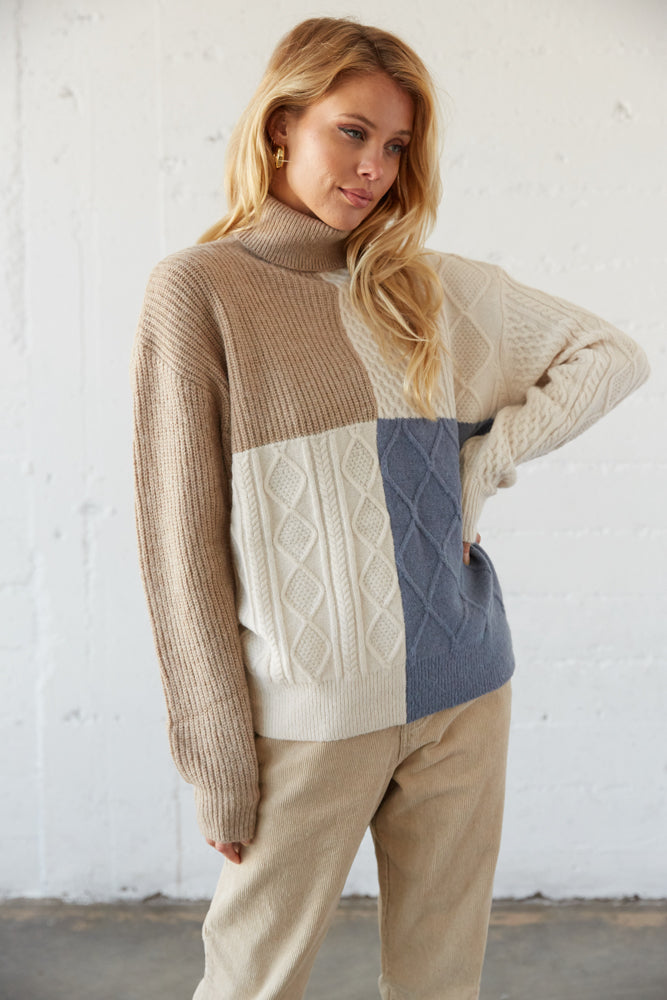 Colorblock turtleneck sweater with cable knit detailing.