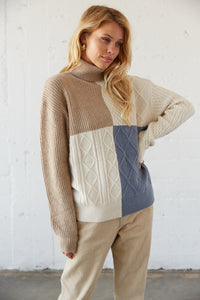 Colorblock turtleneck sweater with cable knit detailing.