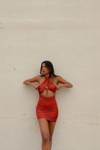 Model posing in rust satin halter dress