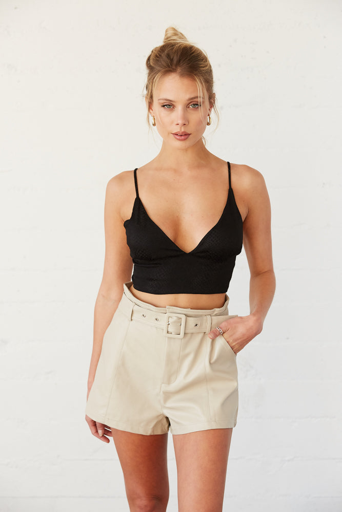 Black crop triangle tank top with tan leather shorts. 