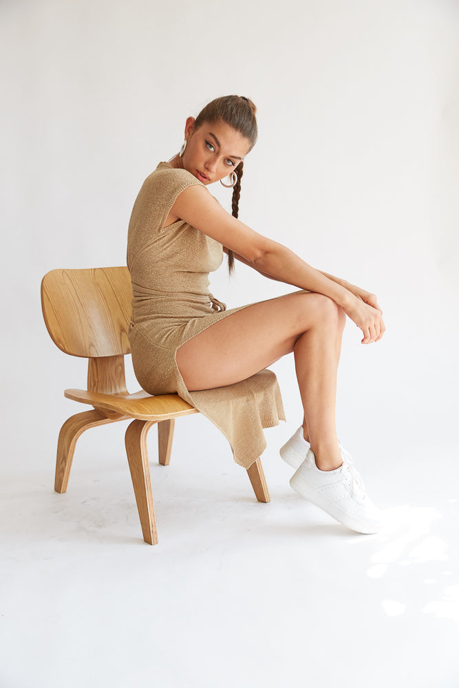 Model sitting wearing beige knit wrap dress