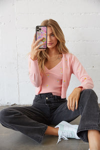 Model taking a mirror selfie in a light pink cardigan set.