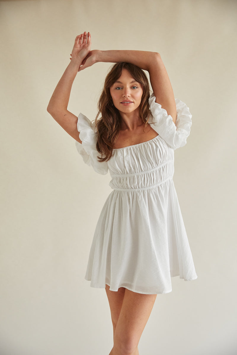 white babydoll dress with puff sleeves Sailoh Sleeve Baby Doll Mini White mini dress Lined Ruffle sleeves Tie feature in back Zipper in back Youll look like an angel in our ethereal Marlina mini dress Bella and Bloom Boutique -